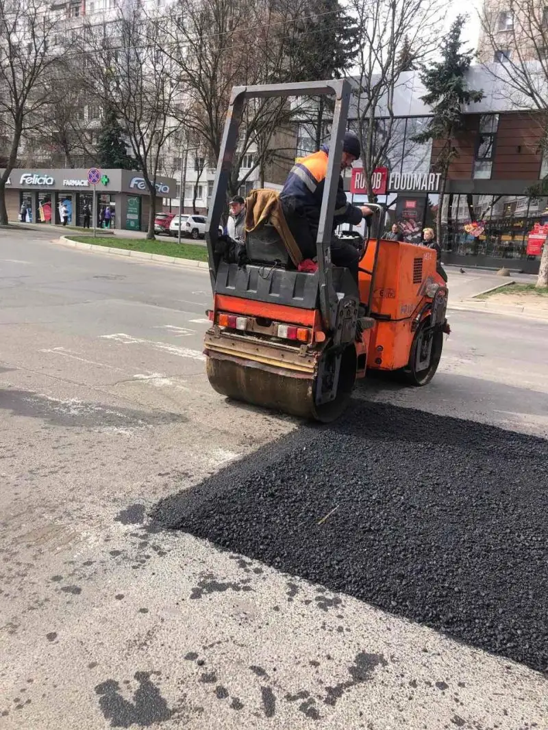 Kisdobos henger tömöríti a frissen bedolgozott meleg aszfalt kátyúbetétet városi úton